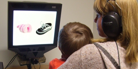  A toddler sitting on his mom’s lap watches the  disfluency study movie on the Tobii Pro screen based eye tracker.