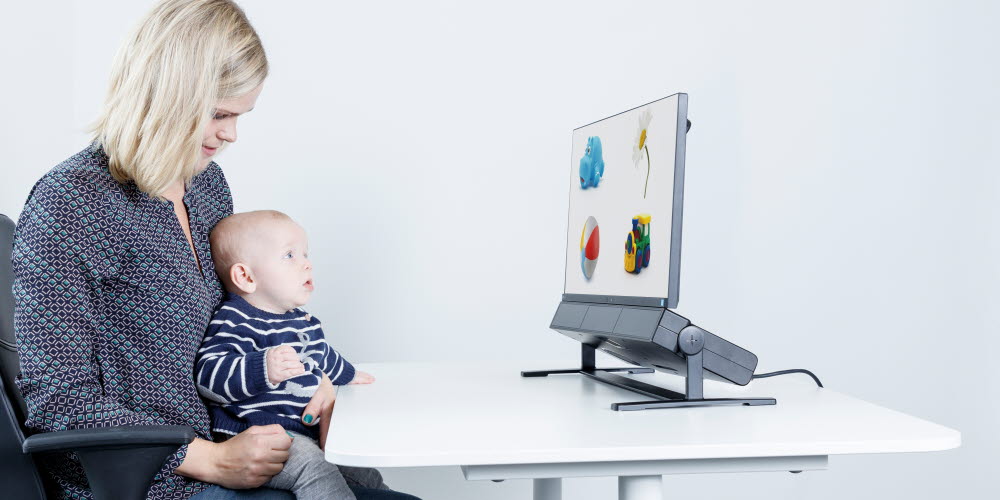 Woman holding a baby using an eye tracker for child development