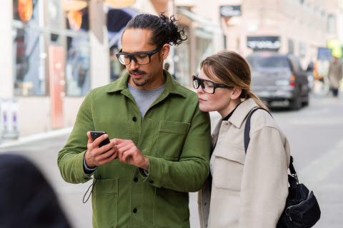 Two people using wearable eye trackers to look at a mobile phone